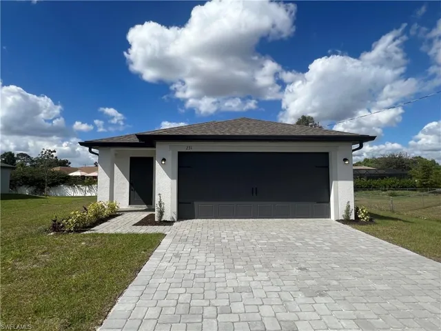 View of front of property with decorative driveway, stucco siding, and an attached garage