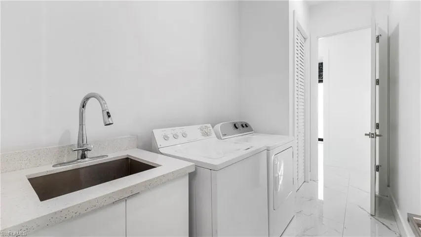 Laundry room with light marble finish flooring and washer and dryer