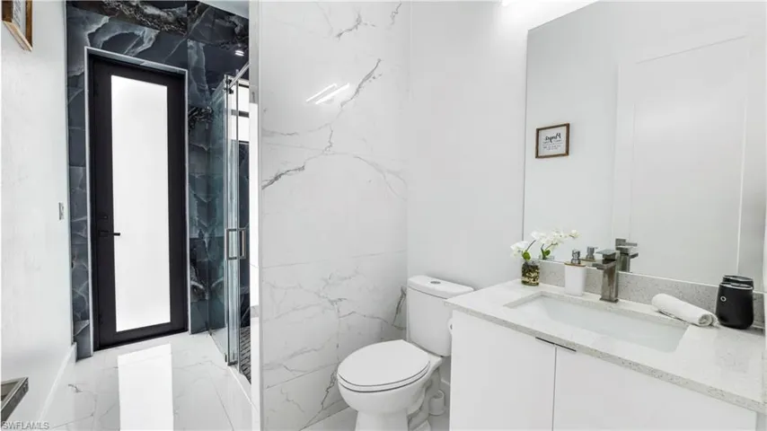 Bathroom with vanity and a marble finish shower
