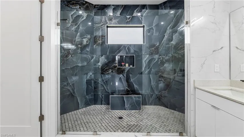 Full bath featuring a marble finish shower and vanity