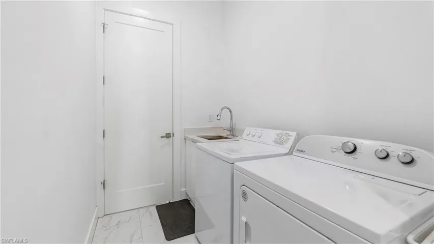 Laundry area with light marble finish flooring and separate washer and dryer
