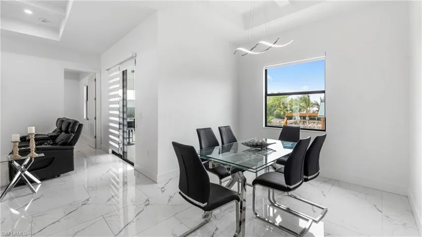 Dining space featuring light marble finish flooring and a tray ceiling