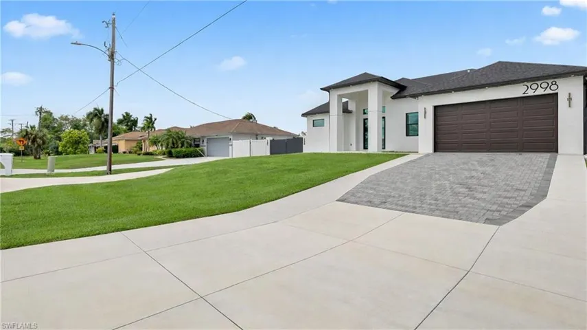 View of front of property with a front lawn, stucco siding, driveway, and a garage