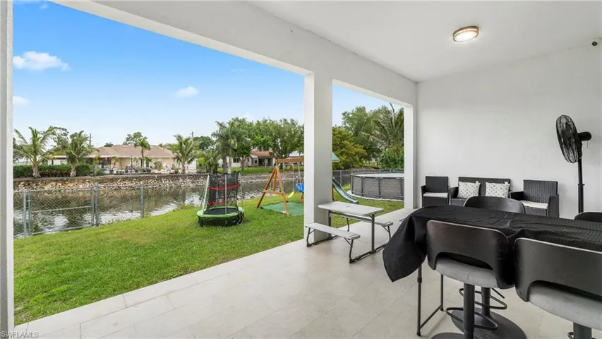 Fenced backyard with a patio, outdoor dining space, a playground, a trampoline, and a water view