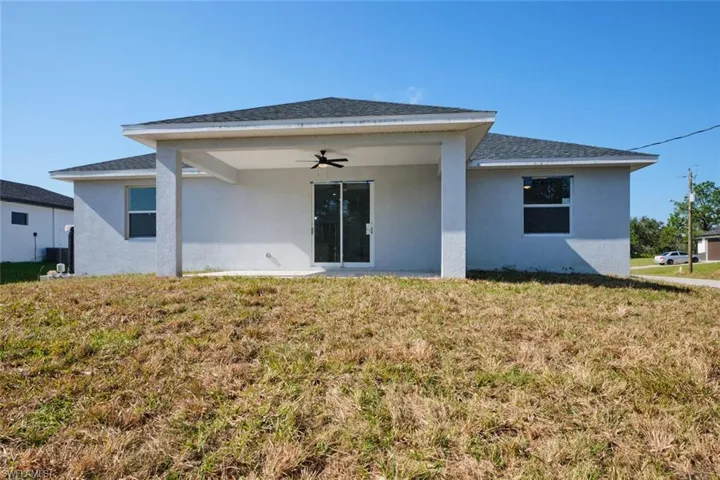 Rear view of house featuring a lawn and ceiling fan