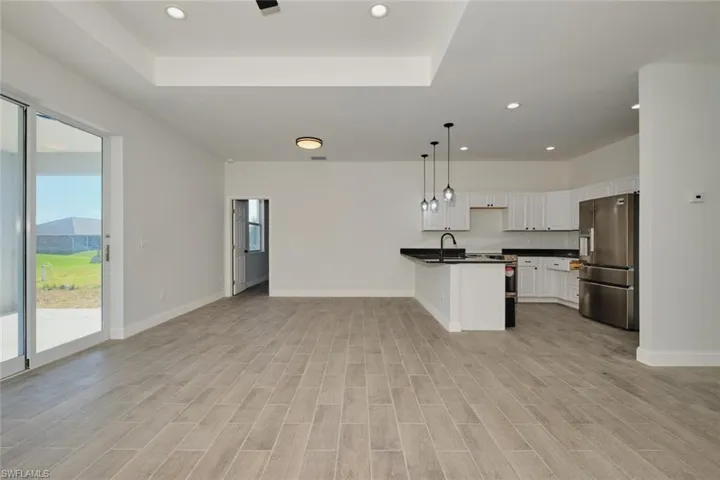 Kitchen with stainless steel refrigerator with ice dispenser, white cabinetry, hanging light fixtures, and plenty of natural light