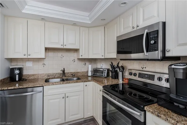 Kitchen with stainless steel appliances, sink, and white cabinetry