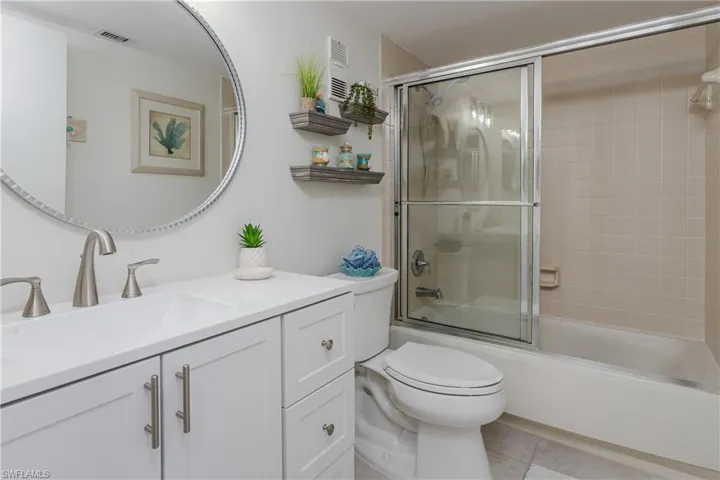 Full bathroom featuring combined bath / shower with glass door, vanity, toilet, and tile patterned flooring