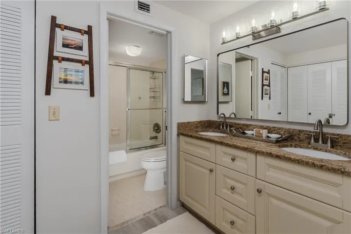 Full bathroom with bath / shower combo with glass door, vanity, toilet, and tile patterned floors