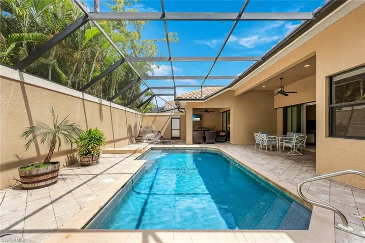 Side view of the screened in lanai, pool, outdoor dining and kitchen, and plenty of sitting area