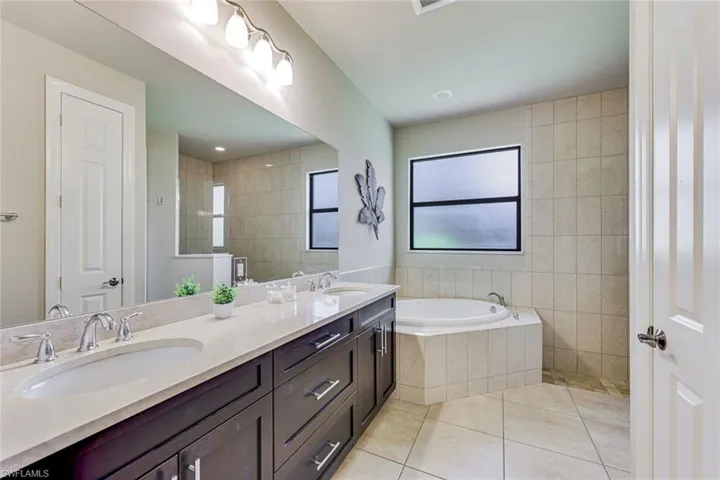 Master bathroom showing dual vanities, bathtub and window