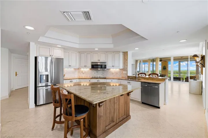 Kitchen with a breakfast bar area, a peninsula, light stone counters, stainless steel appliances, and decorative backsplash