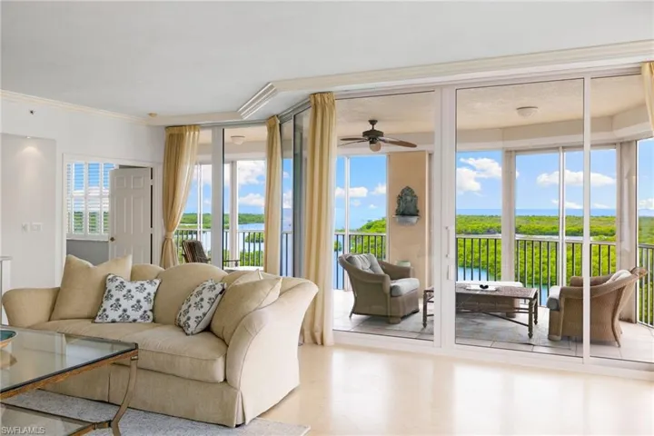 Living room featuring a water view, ornamental molding, and a ceiling fan