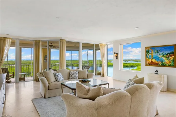 Living room with crown molding, plenty of natural light, a water view, and a wall of windows