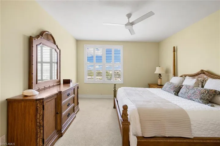 Bedroom with multiple windows, light colored carpet, and a ceiling fan