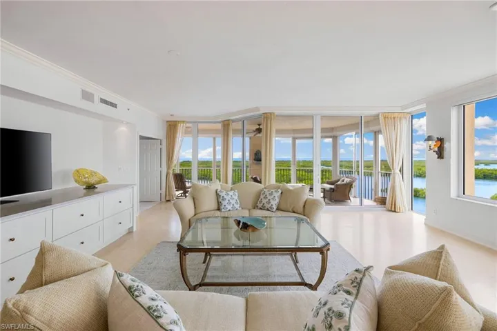 Living area with a wall of windows, crown molding, a water view, and ceiling fan