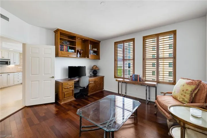Office with built in study area and dark wood-style flooring