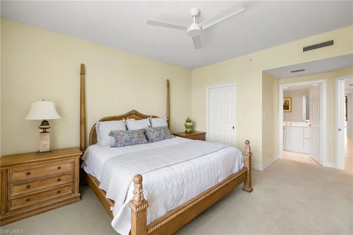 Bedroom with light colored carpet, a ceiling fan, and ensuite bathroom