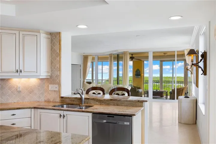 Kitchen featuring backsplash, dishwasher, open floor plan, light stone countertops, and a peninsula