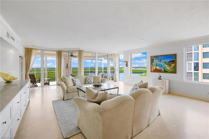 Living area featuring crown molding, a wall of windows, light flooring, and a water view