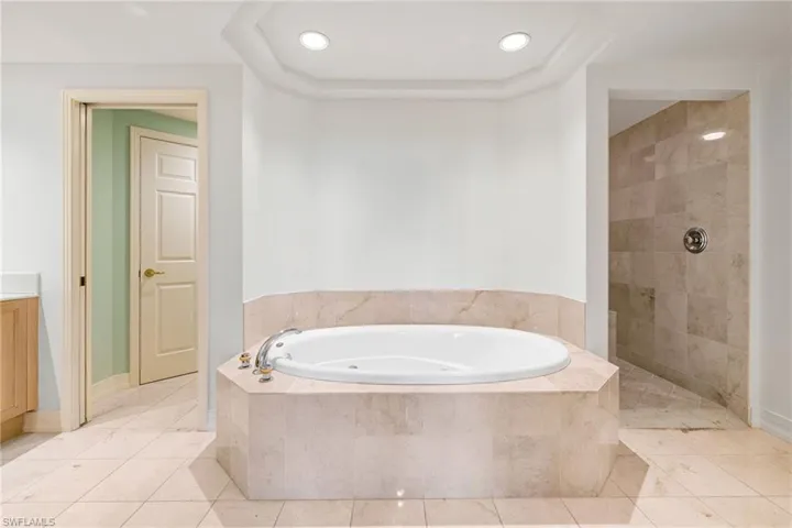 Bathroom with a garden tub, light tile patterned floors, walk in shower, vanity, and recessed lighting