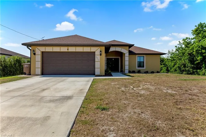 Prairie-style home with a front lawn, driveway, a shingled roof, an attached garage, and stucco siding