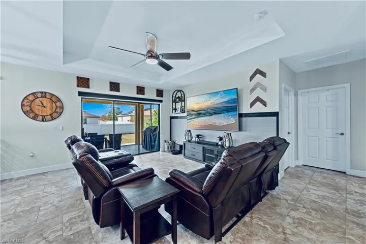 Living area featuring attic access, a ceiling fan, baseboards, and a raised ceiling