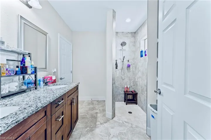 Bathroom featuring double vanity, baseboards, a sink, and a walk in shower