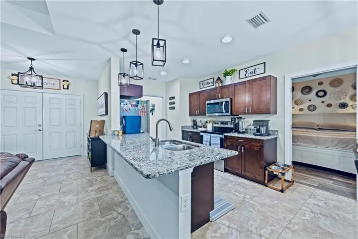 Kitchen featuring stainless steel appliances, visible vents, a sink, dark brown cabinetry, and a peninsula