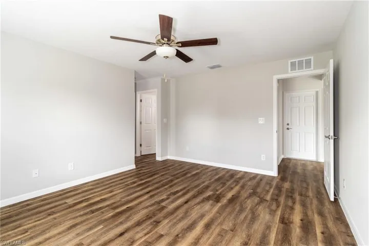 Empty room with dark wood-style flooring and a ceiling fan