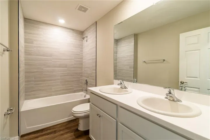 Full bathroom with double vanity, wood finished floors, and bathing tub / shower combination
