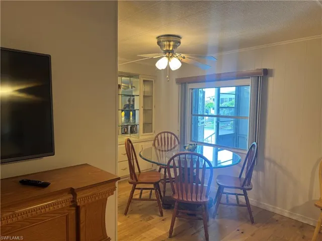 Dining area featuring wood-finish flooring, a ceiling fan with integrated lighting, and a prominent window