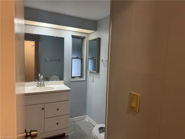 Bathroom featuring a white vanity with an integrated sink, polished chrome faucet, and a wall-mounted mirror