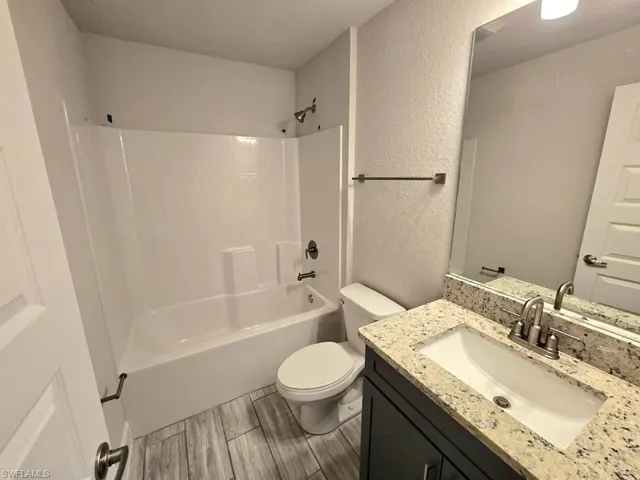 Full bathroom with toilet, hardwood / wood-style floors, vanity, and tub / shower combination