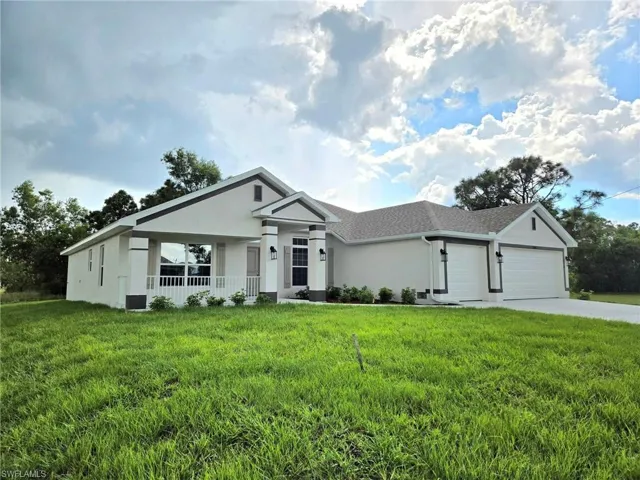 Ranch-style home with a front yard, a garage, and a porch