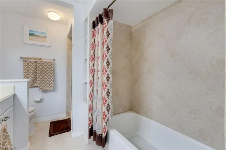 Bathroom with vanity, light tile patterned floors, and shower / tub combo with curtain