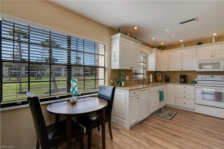 Kitchen with white appliances, white cabinetry, light wood finished floors, and recessed lighting