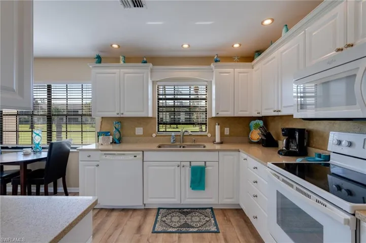 Kitchen featuring white appliances, white cabinetry, light wood-style flooring, recessed lighting, and light stone countertops