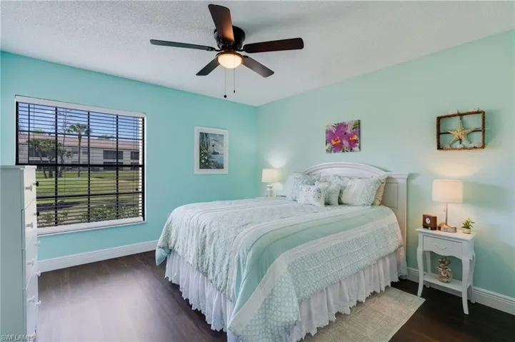 Bedroom with a textured ceiling, dark wood finished floors, and a ceiling fan