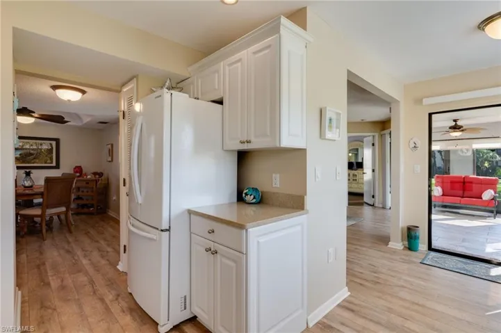 Kitchen with a ceiling fan, white cabinets, light wood-style floors, and light stone countertops