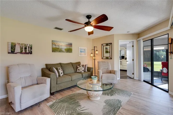 Living room featuring a textured ceiling, ceiling fan, and wood finished floors