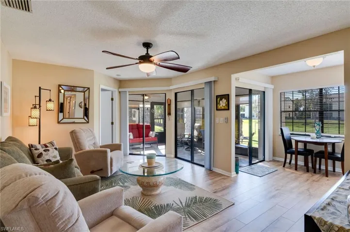 Living room featuring wood finished floors, a textured ceiling, plenty of natural light, a ceiling fan, and french doors