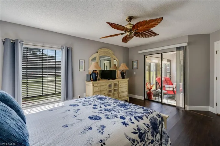 Bedroom with a textured ceiling, dark wood-style floors, a ceiling fan, and access to outside