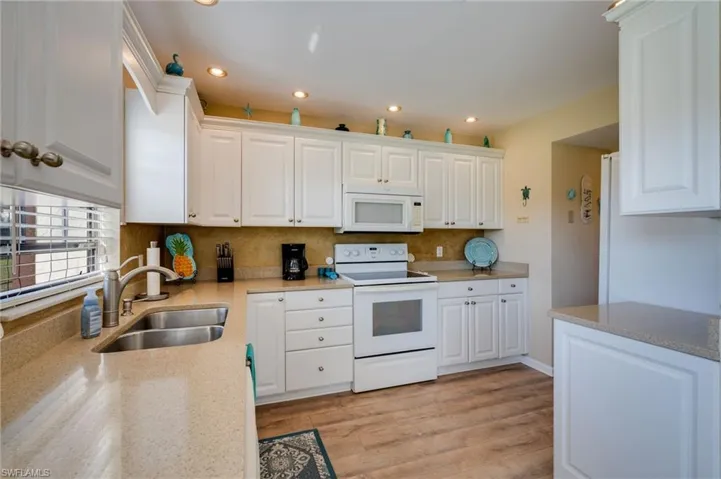 Kitchen featuring white appliances, white cabinetry, light stone countertops, light wood finished floors, and recessed lighting