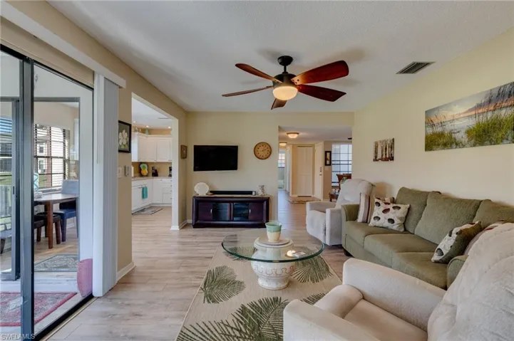 Living area featuring light wood finished floors, ceiling fan, and a textured ceiling