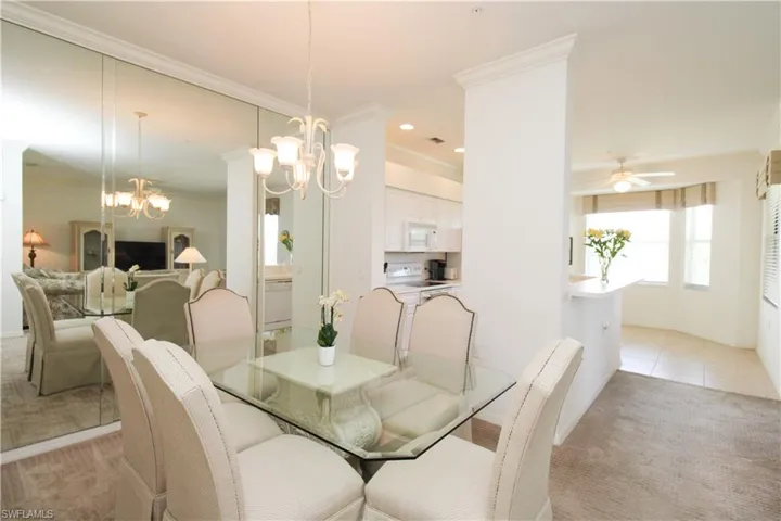 Carpeted dining room featuring ceiling fan with notable chandelier and crown molding