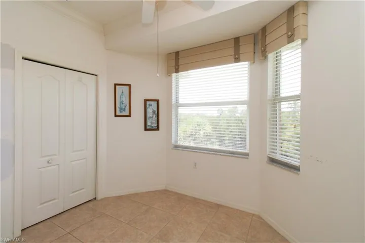 Unfurnished bedroom with multiple windows, light tile patterned floors, ceiling fan, and a closet