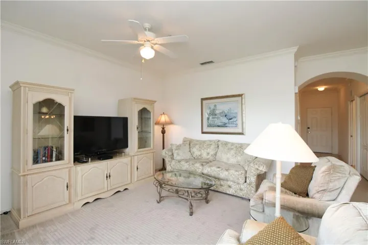 Carpeted living room with ornamental molding and ceiling fan