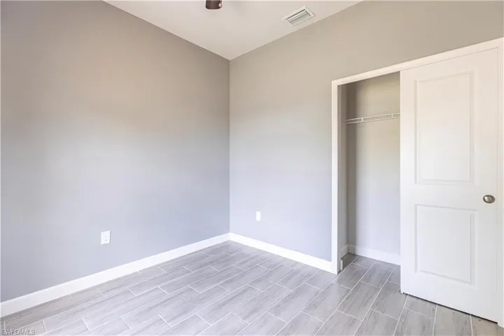 Unfurnished bedroom featuring baseboards, wood finish floors, and a closet