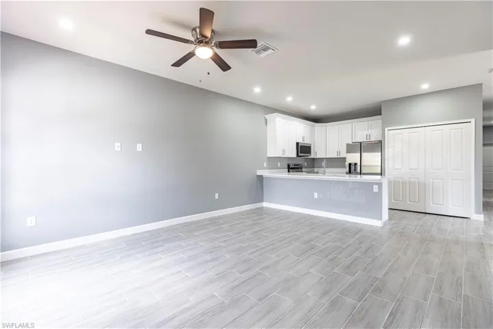 Kitchen featuring appliances with stainless steel finishes, ceiling fan, a peninsula, light countertops, and baseboards
